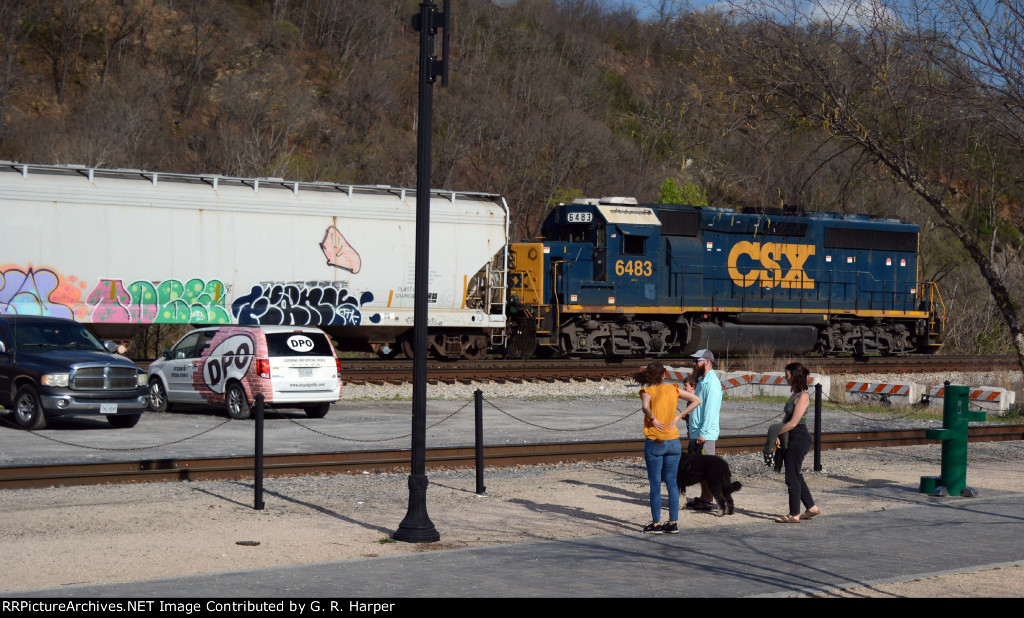 A family taking advantage of the weather and walking opportunities in downtown Lynchburg pauses to watch CSX local L206 drift by,